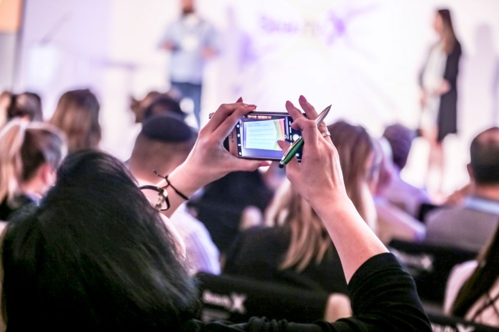 An attendee at the 2018 BeautyX Retail grabbing shots of the Amazon.com presentation.