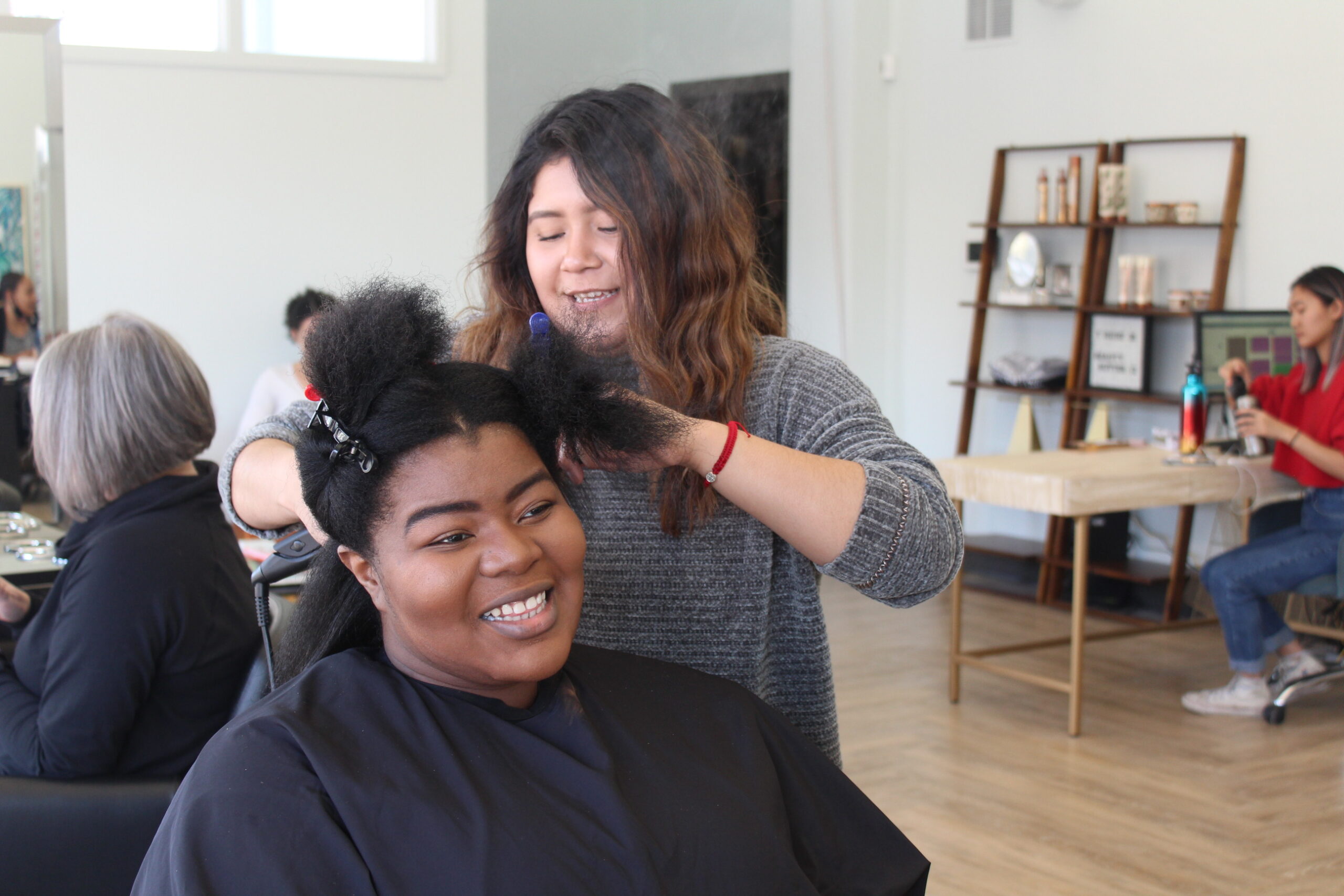 Stylist Stephanie Pacios works on client Joal Reeves's hair.