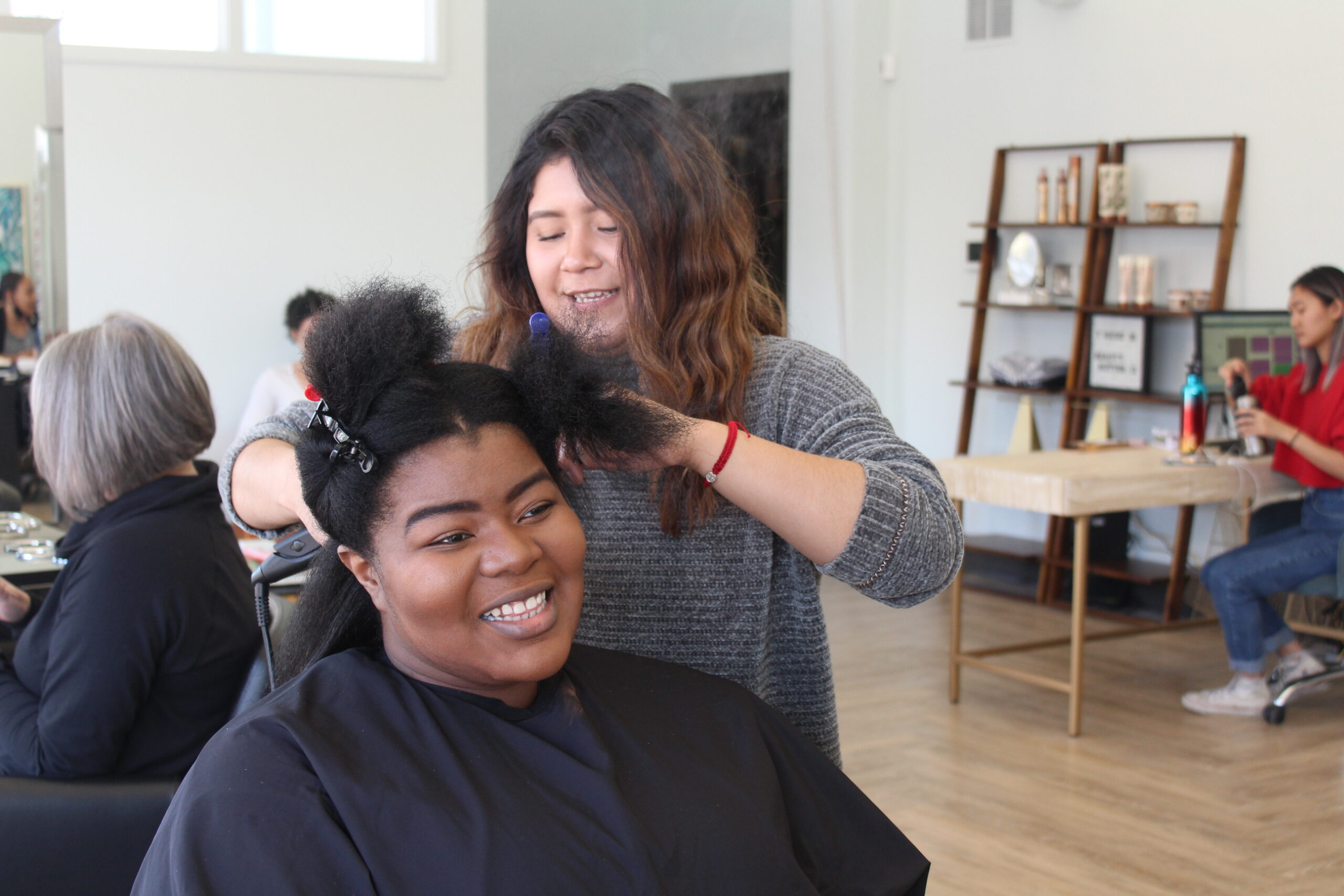 Stylist Stephanie Pacios works on client Joal Reeves's hair. 